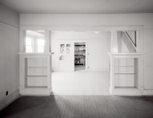 Interior of bungalow style home that has wooden floors, column bases, and has a whitewash kind of color.