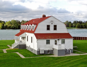 Exterior of dutch colonial style house that has six gable dormers, one covered porch, one uncovered porch, and one chimney.