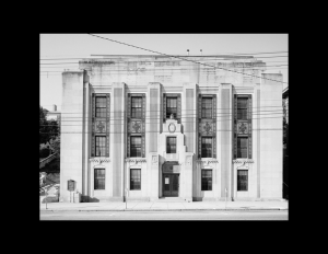 Stone building with art deco style windows, decorative panels, and angular geometry.