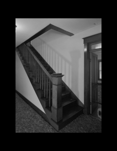 Interior of house featuring bungalow style hardwood floor staircase, along with wooden stair mouldings.