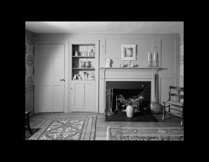 Interior of cape cod style room with door mouldings, cabinetry mouldings, and fireplace mouldings on accent wall.