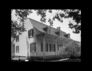 Exterior with dutch colonial style that has gable dormers on roof, window mouldings with shutters, and a covered porch with pillars.