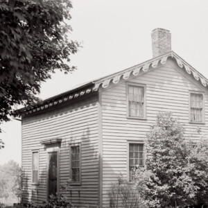 Exterior of Arnold house features shingle siding, window mouldings, cornice mouldings, door mouldings, and an all brick chimney.