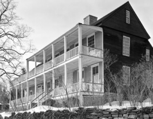 Exterior of new england colonial style building complex featuring a steep roof, and balconies connecting all the rooms accompanied with railing.