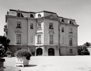 French city style house showcasing dormer on curved roof, brick exterior with tall second-story windows with arched tops and mouldings.