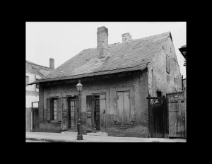 Old french colonial style house featuring an all brick exterior, steep roof, and a couple chimneys.