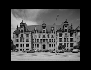 French city style building showcasing dormers, four stories of window mouldings, brick exterior, and a steep roof.