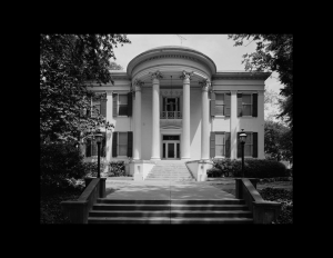 Greek revival style building with oval roof accompanied with huge pillars, and steps leading to the entrance of the building.