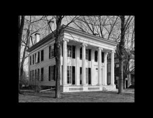 Greek revival style building with exterior cornice mouldings, huge pillars, steps leading to the entrance, and windows with shutters.