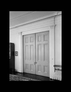 Interior of greek revival style room featuring hardwood floors, door mouldings, and interior cornice mouldings.