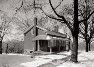 Birthplace of Thomas Edison house exterior with covered front porch, cornice mouldings, window mouldings with shutters, and overhanging roof.