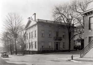 Exterior of curtis devin house showcasing balustrades on roof, side balcony, brick walls, door columns along with railed steps to entrance.