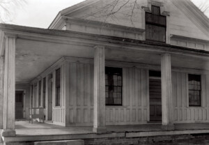 Close up of Freer house exterior showcasing covered wrap around porch along with columns and exterior cornice mouldings.