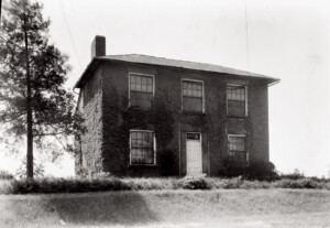 Exterior of Hardwick House featuring double windows, all brick exterior, stone foundation, and front doorway with door panel molds.