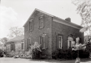 Exterior of Hopwood House featuring brick wall, window casing with shutters, and door casing with window casing and panel molds.