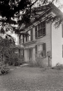 Exterior of Hopkins House featuring window casing with shutters, and doorway with window casing, column detail, and cornice mouldings.