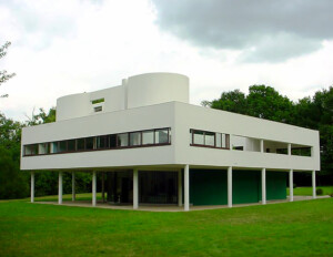 International style building that is rectilinear, asymmetrical, white and has a covered ground level with open spaces divided by columns.