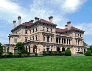 Four story italian renaissance style castle featuring many chimneys, balconies, columns, cornice mouldings, and a low pitched hipped roof.