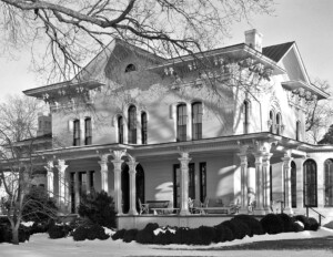 Italianate style house with hipped roof, beautiful cornice mouldings, tall windows, and a covered front porch with columns.