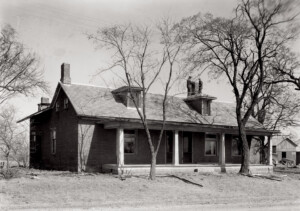 Exterior of Matt Gray House featuring a covered porch, doors with panel molds, dormers on roof, three chimneys, and shingle siding.