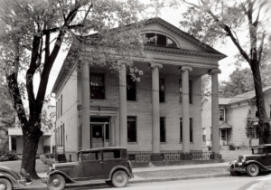 Exterior of Moore Brewster House with covered front porch with columns, exterior cornice mouldings, and window casing on roof.