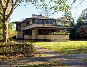 Side angle of prairie style house with low-pitched hipped roof, and a bank of beautiful window mouldings.