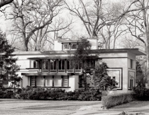 Prairie style house with flat roof, bank of window mouldings, and stucco exterior.