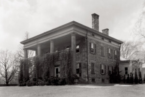 Exterior of Simon Perkins House south east elevation featuring tall windows with shutters, chimneys on roof, flat roof and large pillars with mouldings