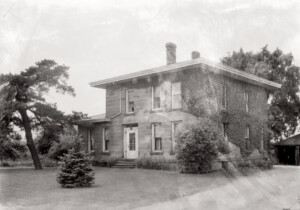 Exterior of WM Baldauf House front door casing with column detail, door casing with panel molds, windows with shutters and chimneys on the roof