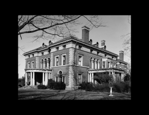 Angular italian renaissance style house with window mouldings, steps to entrance along with a circular covered porch entrance with columns.