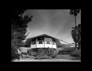 Mid century style house with flat roof that is slanted, and hexagon sunroom with window mouldings.