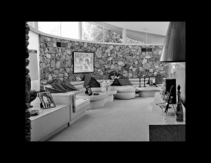 Interior of mid century style room that features rock walls, and window mouldings outlining the room close to the ceiling.