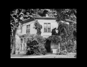 Octagonal plan style house that is mostly covered with moss, accompanied with beautiful window mouldings.