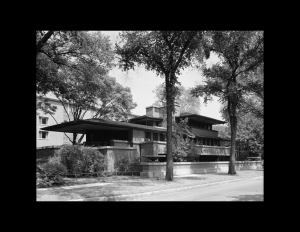 Prairie style house with low-pitched hipped roof, cornice mouldings, wide roof eaves, and stucco exterior.