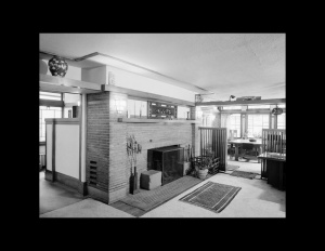 Interior of prairie style house with brick fireplace, and window mouldings.