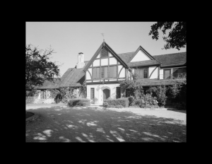 Tudor style house with hipped roof, window mouldings, and door mouldings.