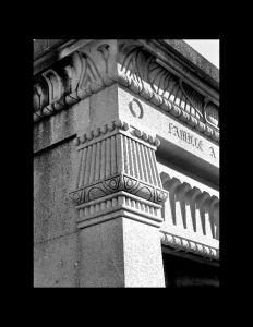 Close up of exterior egyptian revival style building featuring an egyptain revival style exterior stone cornice and stone column.