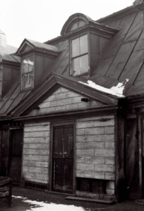 Exterior of BENJAMIN PICKMAN HOUSE front-side featuring shingle siding, gable dormers, slanted roof, and window casing mouldings.