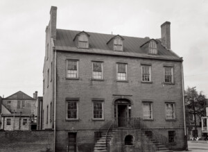 Photo from the south elevation of the home facing State Street. Split entranceway entering the home with dormer details on the attic floor.